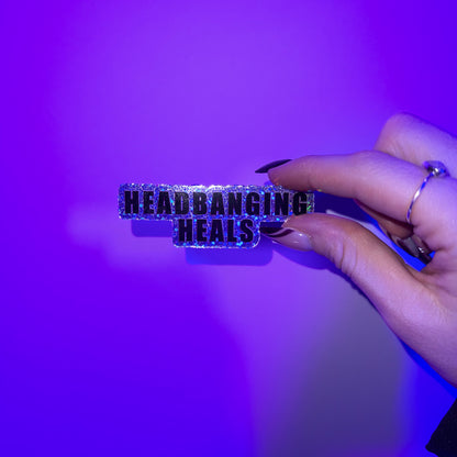 Studio shot of Headbanging Heals Glitter Dubstep Sticker in hand